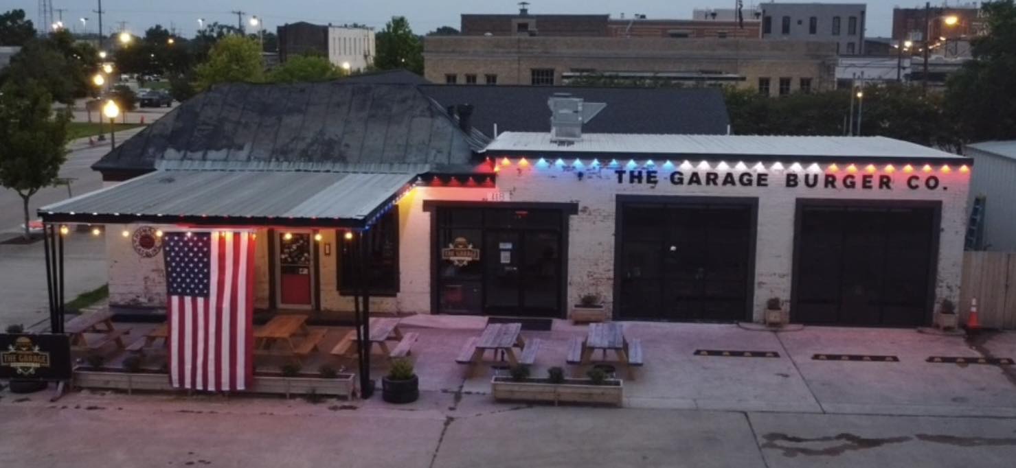 The Garage Burger Co. storefront at dusk, lit up in red, white and blue lights