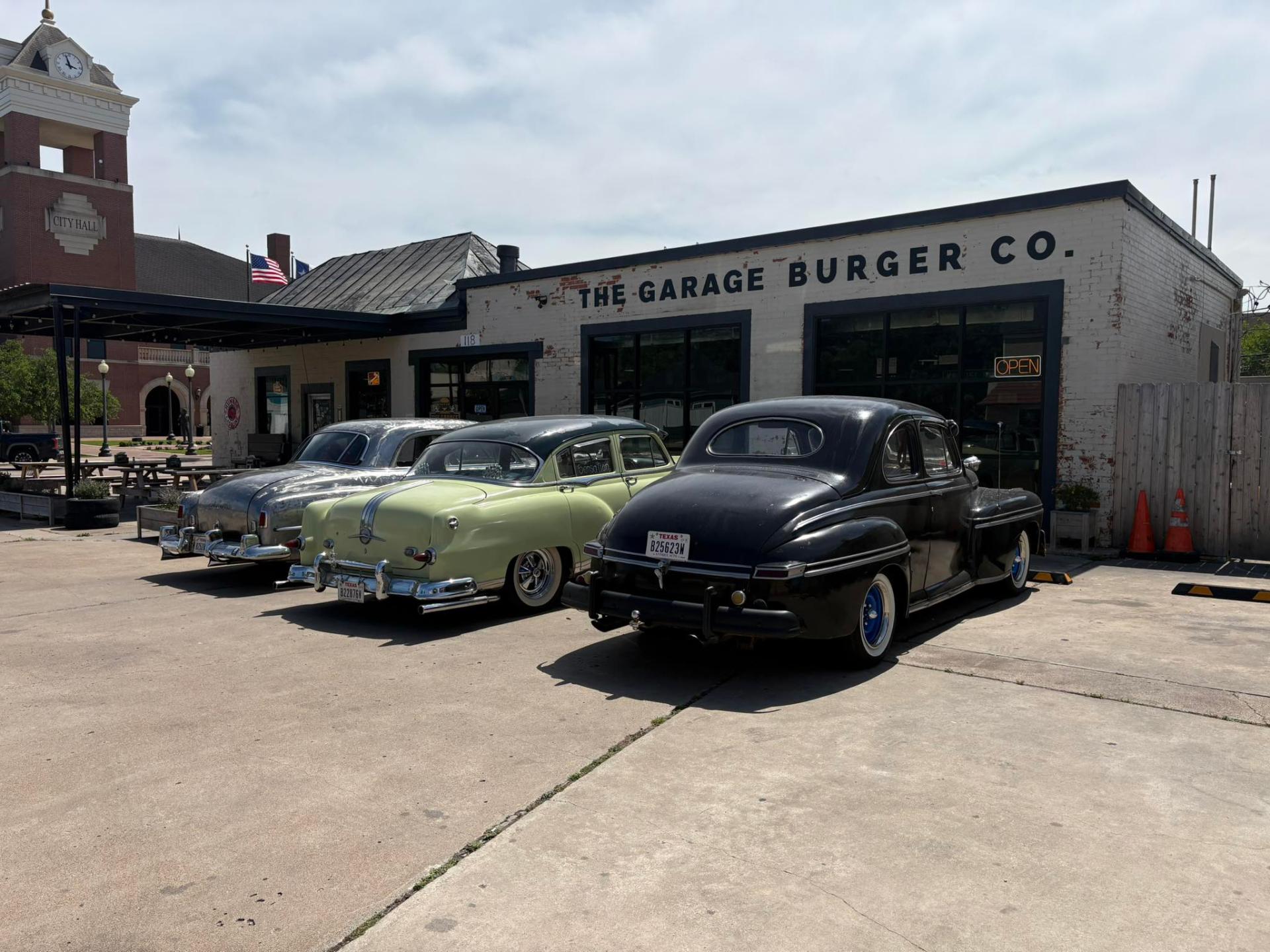Classic cars parked outside The Garage Burger Co. in downtown Navasota